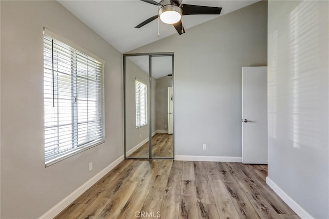 unfurnished bedroom with a ceiling fan, baseboards, vaulted ceiling, a closet, and light wood-type flooring