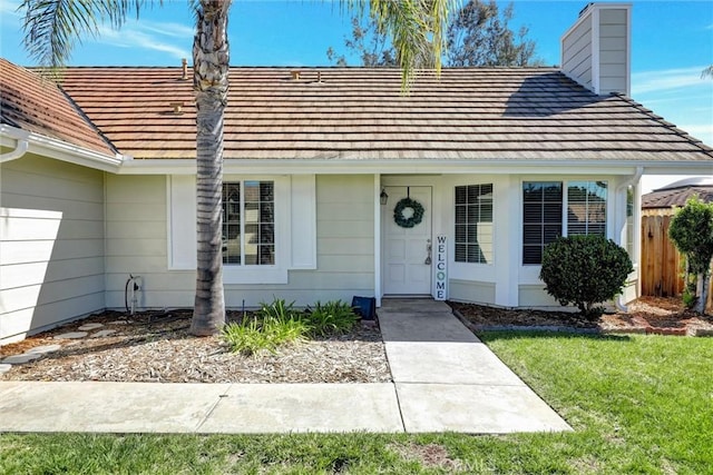 view of front of property with a chimney, fence, and a front lawn