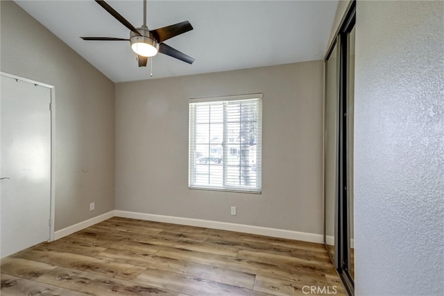 unfurnished bedroom with lofted ceiling, a ceiling fan, baseboards, and wood finished floors