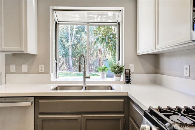 kitchen featuring light countertops, appliances with stainless steel finishes, a sink, and a healthy amount of sunlight