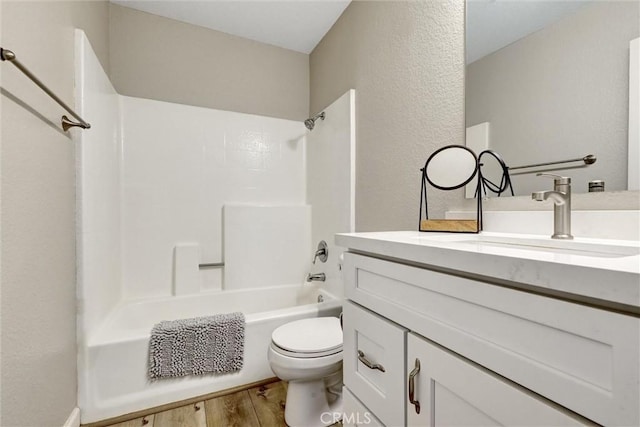 full bathroom featuring a textured wall, shower / bathing tub combination, toilet, vanity, and wood finished floors