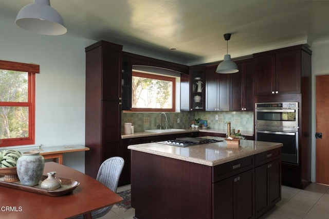 kitchen featuring stainless steel double oven, a sink, gas stovetop, decorative backsplash, and pendant lighting