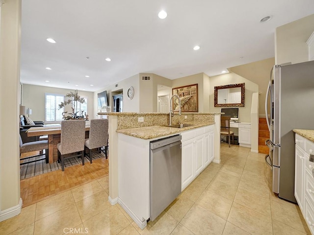 kitchen featuring light tile patterned floors, white cabinetry, appliances with stainless steel finishes, and a sink