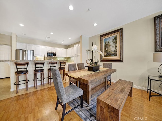 dining room featuring recessed lighting, light wood-style flooring, and baseboards