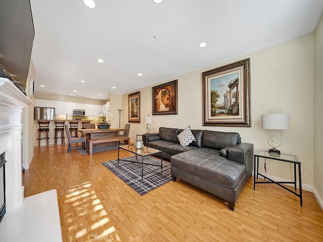 living room with baseboards, a fireplace, light wood-style flooring, and recessed lighting