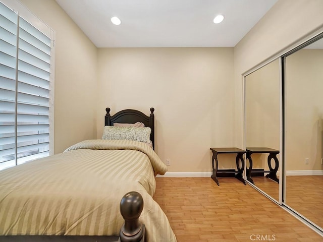 bedroom featuring recessed lighting, a closet, light wood-style flooring, and baseboards