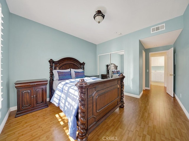 bedroom with a closet, light wood-type flooring, visible vents, and baseboards