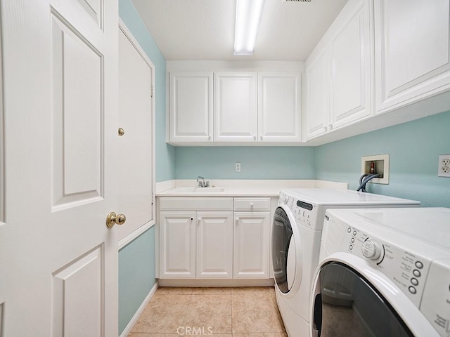 laundry area featuring light tile patterned floors, a sink, cabinet space, and washer and dryer