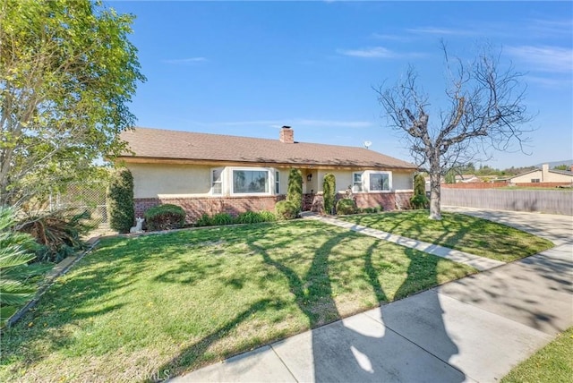 ranch-style house with brick siding, fence, a front lawn, and stucco siding