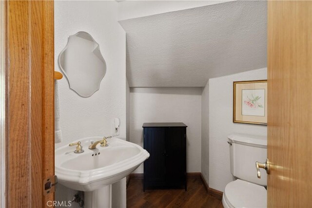 half bathroom with baseboards, toilet, wood finished floors, a textured ceiling, and a sink