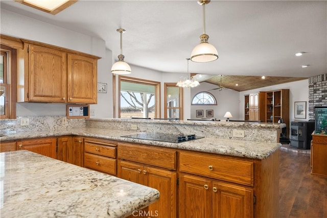 kitchen featuring light stone counters, brown cabinetry, a peninsula, lofted ceiling, and black electric cooktop