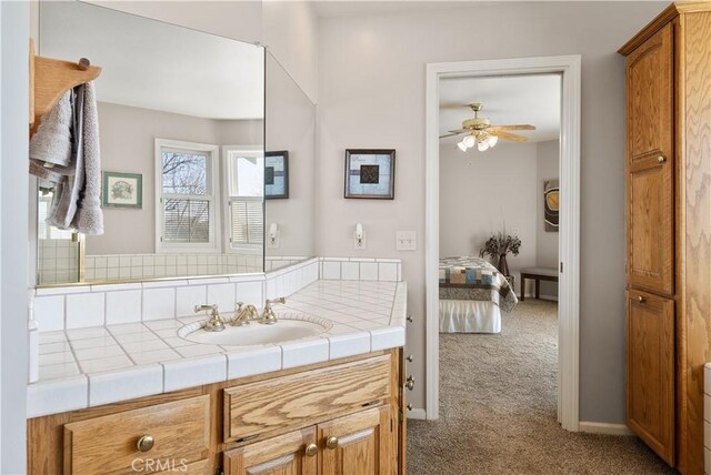 bathroom with baseboards, ensuite bath, ceiling fan, and vanity