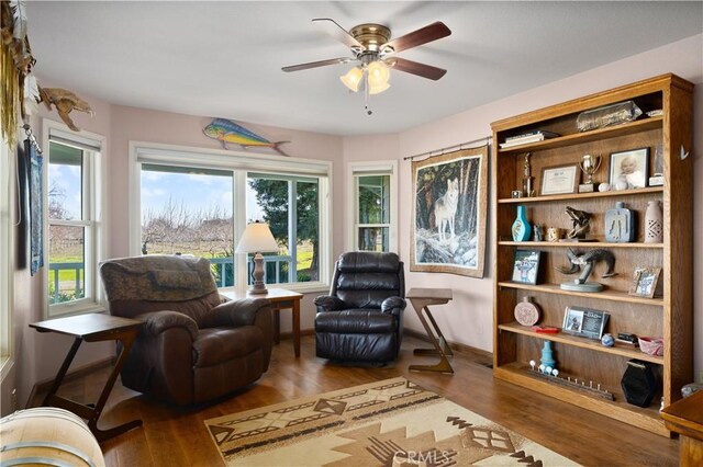 living area featuring ceiling fan, baseboards, and wood finished floors