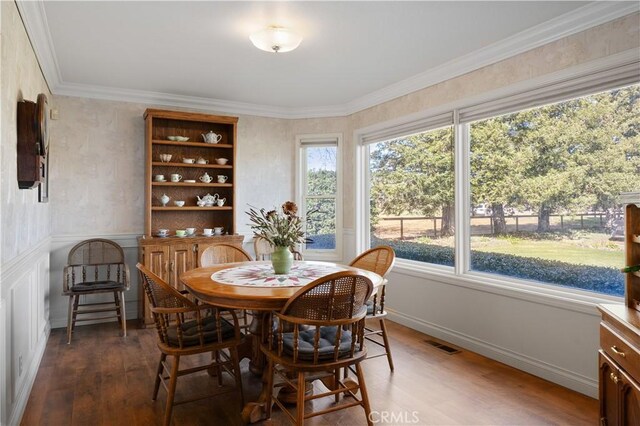 dining room featuring visible vents, baseboards, wood finished floors, and ornamental molding