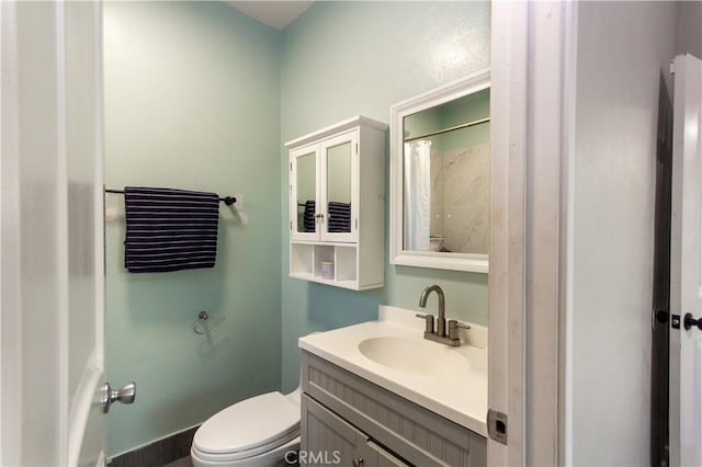 bathroom featuring baseboards, vanity, and toilet