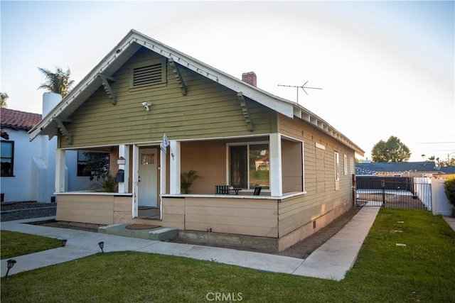 view of front of home featuring a porch, a chimney, a front lawn, and fence