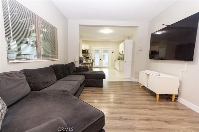 living room with french doors, light wood-style flooring, and baseboards