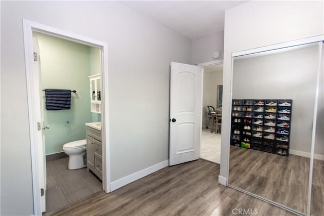 bathroom with toilet, baseboards, and wood finished floors