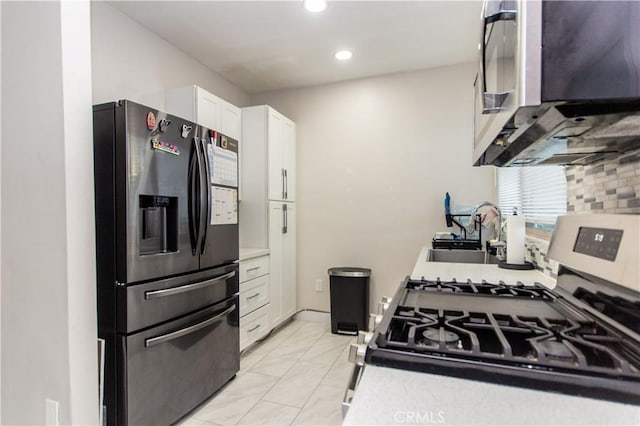 kitchen featuring stainless steel range with gas cooktop, backsplash, white cabinetry, fridge with ice dispenser, and a sink