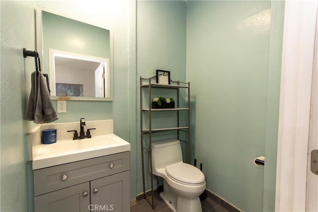 half bathroom featuring toilet, baseboards, and vanity