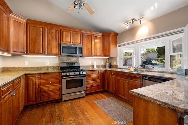 kitchen featuring appliances with stainless steel finishes, dark wood-style flooring, brown cabinets, and a sink