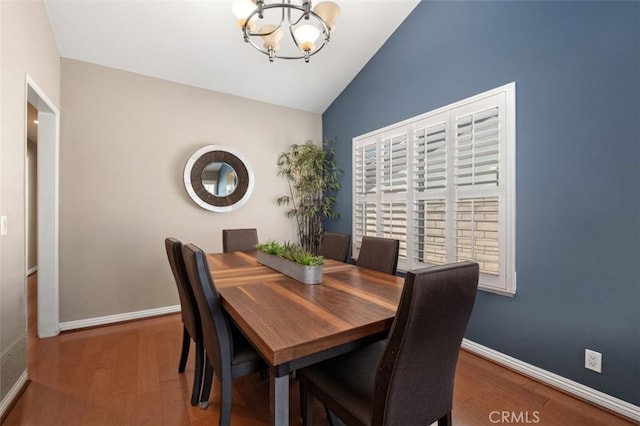 dining area featuring lofted ceiling, wood finished floors, a chandelier, and baseboards