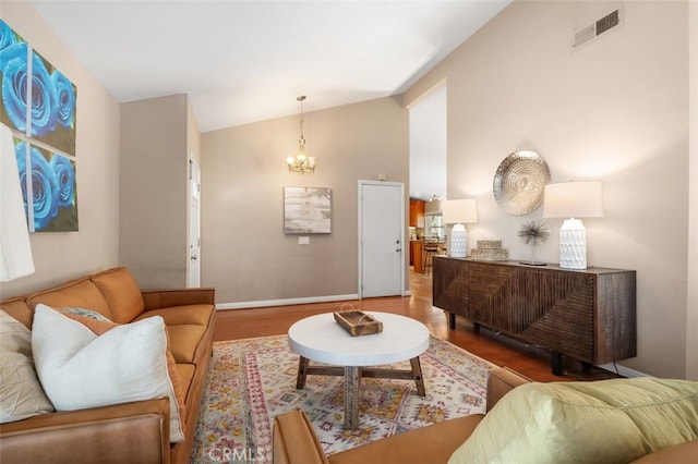 living area with high vaulted ceiling, a notable chandelier, visible vents, and wood finished floors