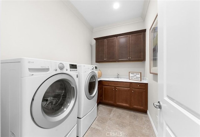 washroom with cabinet space, a sink, ornamental molding, and washer and clothes dryer
