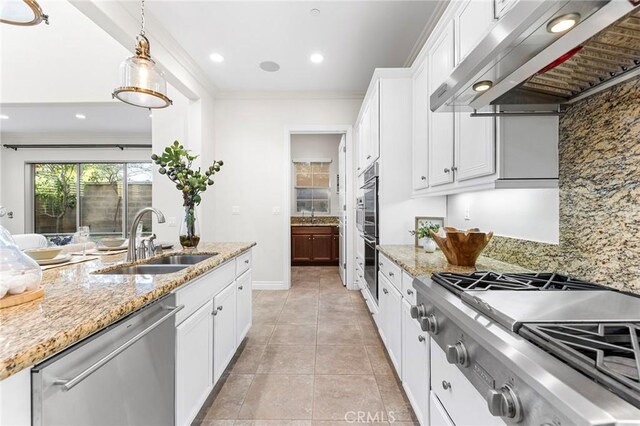 kitchen with white cabinets, ventilation hood, a sink, decorative light fixtures, and appliances with stainless steel finishes