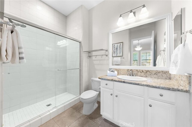 bathroom featuring toilet, vanity, tile patterned flooring, and a stall shower