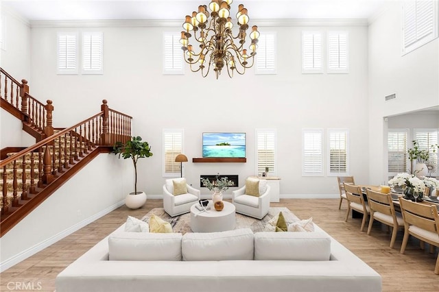 living area with visible vents, baseboards, ornamental molding, stairway, and light wood-type flooring