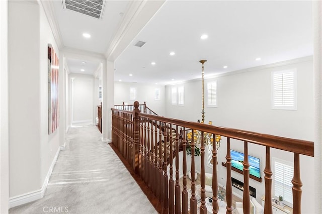 corridor with visible vents, baseboards, light colored carpet, ornamental molding, and an upstairs landing