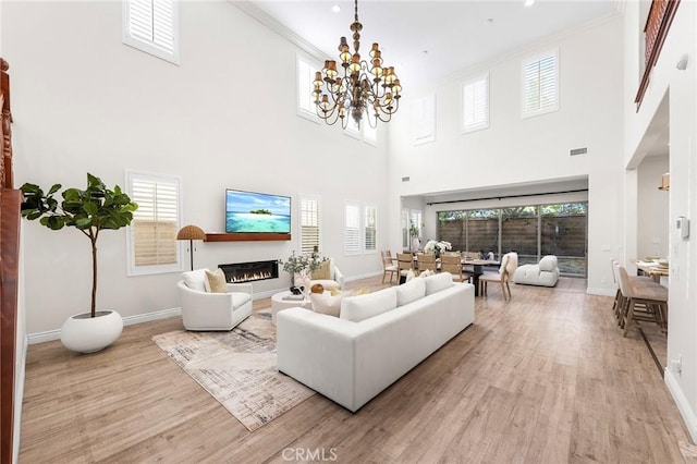 living room with a glass covered fireplace, a healthy amount of sunlight, light wood-style flooring, and baseboards