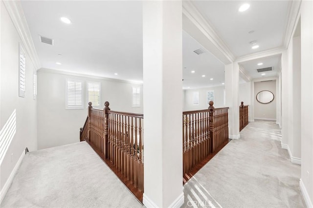 hall with visible vents, an upstairs landing, light colored carpet, and crown molding
