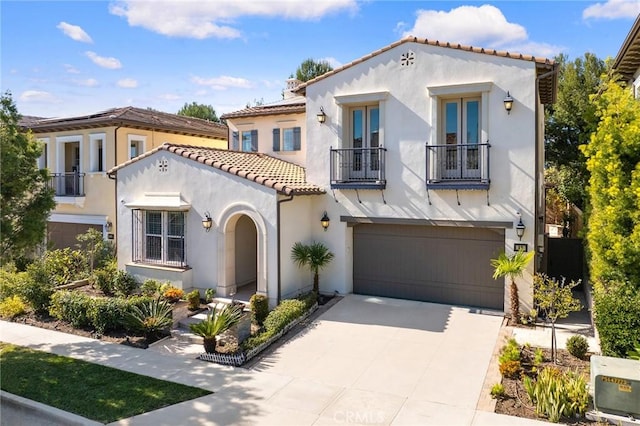 mediterranean / spanish-style house with a garage, concrete driveway, a tile roof, and stucco siding