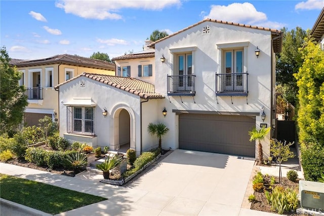 mediterranean / spanish home featuring french doors, a tiled roof, driveway, a balcony, and stucco siding