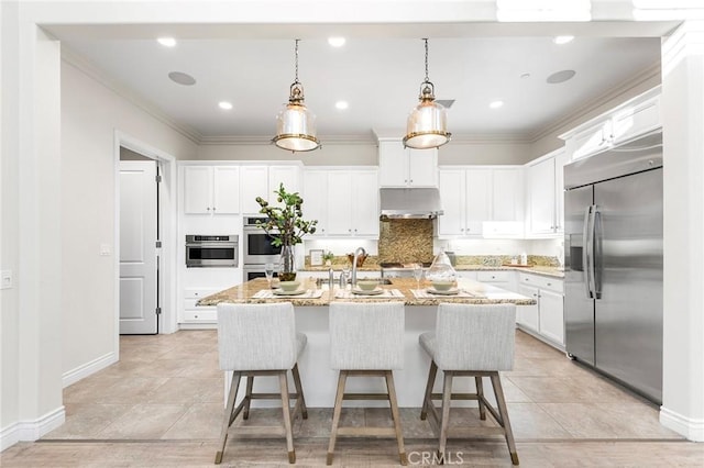 kitchen featuring white cabinets, an island with sink, appliances with stainless steel finishes, under cabinet range hood, and a sink