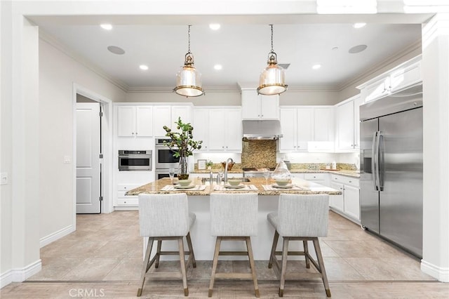 kitchen featuring white cabinets, a kitchen island with sink, a sink, under cabinet range hood, and appliances with stainless steel finishes