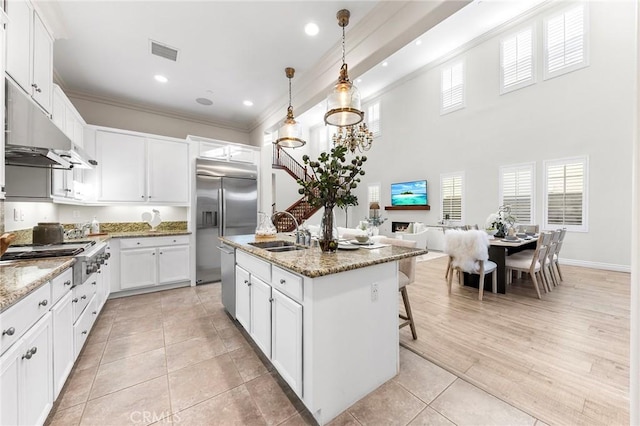 kitchen featuring under cabinet range hood, stainless steel appliances, visible vents, a sink, and crown molding