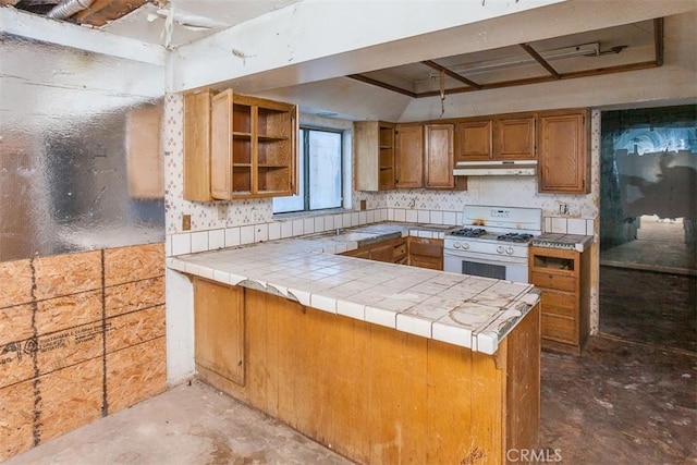 kitchen with brown cabinets, a peninsula, under cabinet range hood, open shelves, and gas range gas stove