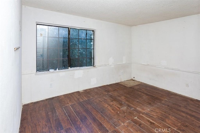 empty room with wood-type flooring and a textured ceiling