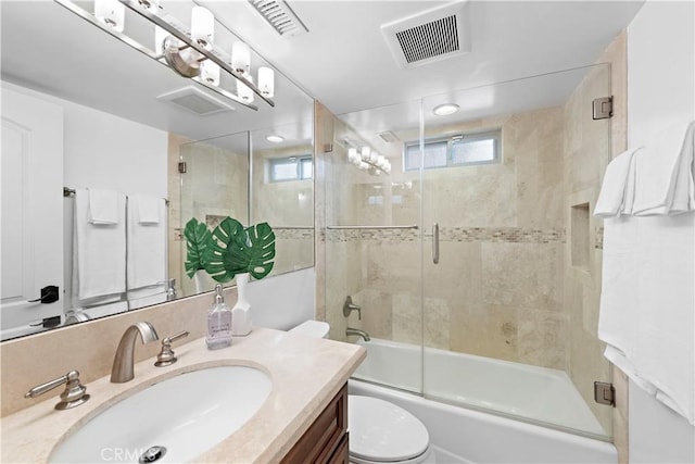 bathroom featuring toilet, bath / shower combo with glass door, vanity, and visible vents