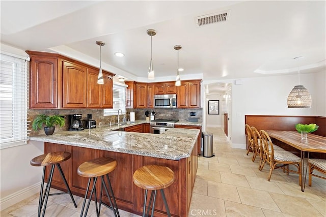 kitchen with light stone counters, a sink, visible vents, appliances with stainless steel finishes, and tasteful backsplash