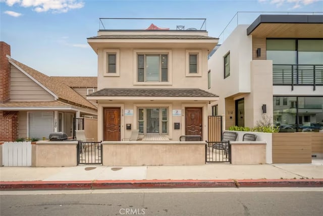 multi unit property featuring a fenced front yard, a gate, and stucco siding