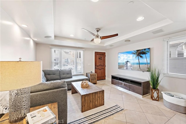 living area featuring light tile patterned floors, a tray ceiling, a ceiling fan, and recessed lighting