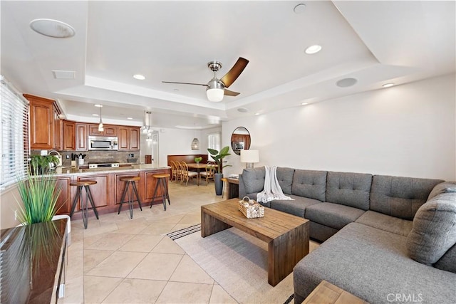 living room with light tile patterned flooring, a raised ceiling, a ceiling fan, and recessed lighting