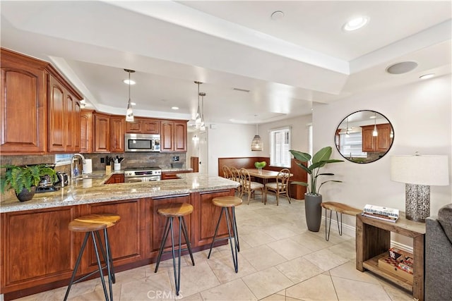 kitchen with stainless steel appliances, decorative backsplash, a sink, light stone countertops, and a peninsula