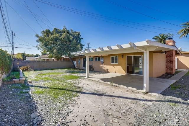 back of house with a chimney, fence, a patio, and stucco siding