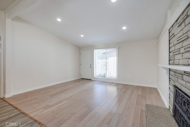 unfurnished living room with a large fireplace, recessed lighting, light wood-style flooring, and baseboards