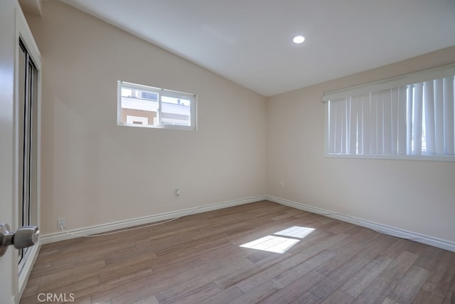 unfurnished room with lofted ceiling, light wood finished floors, and baseboards